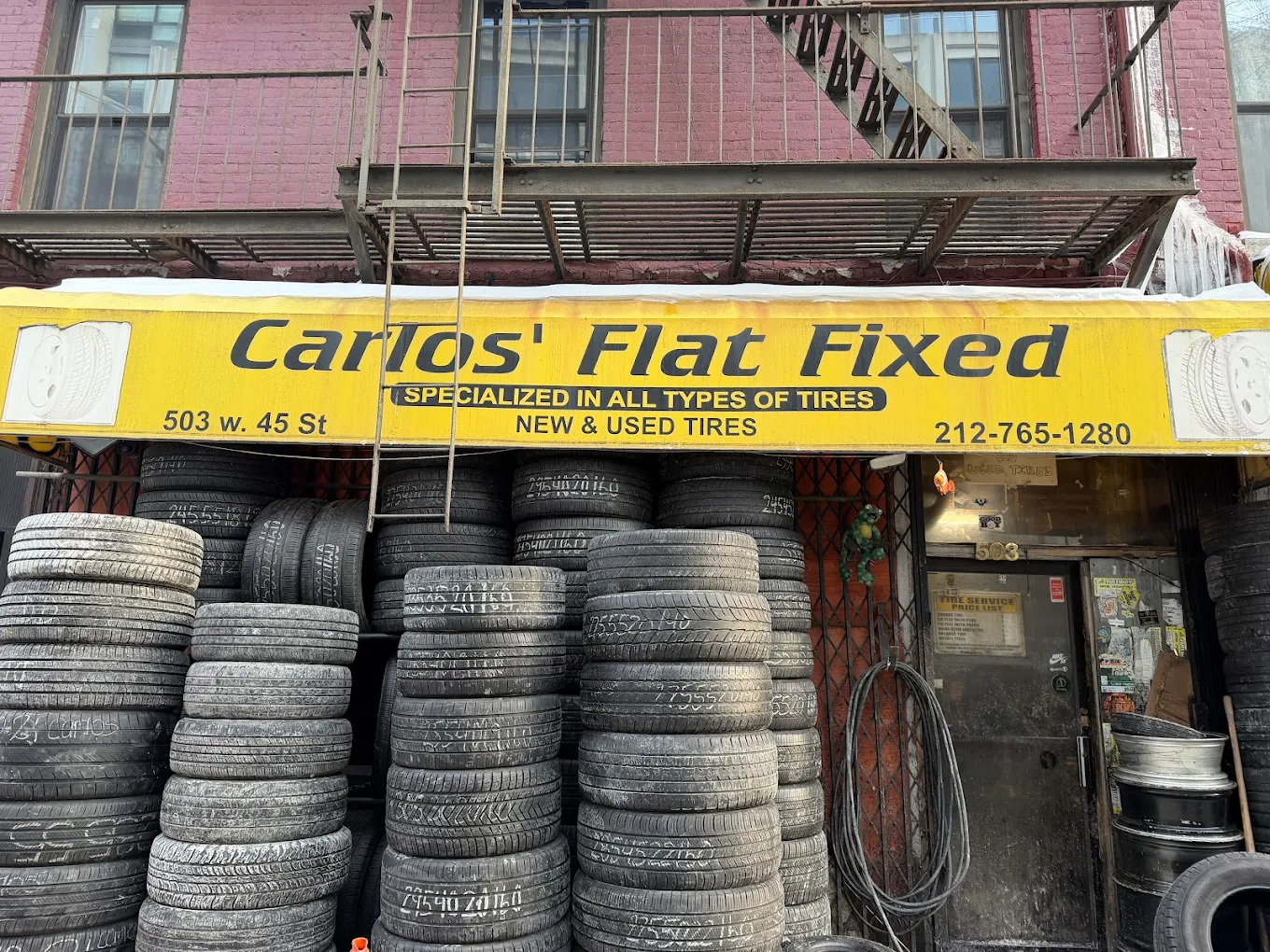 Carlos' Flat Fixed storefront with iconic yellow sign and stacked tires
